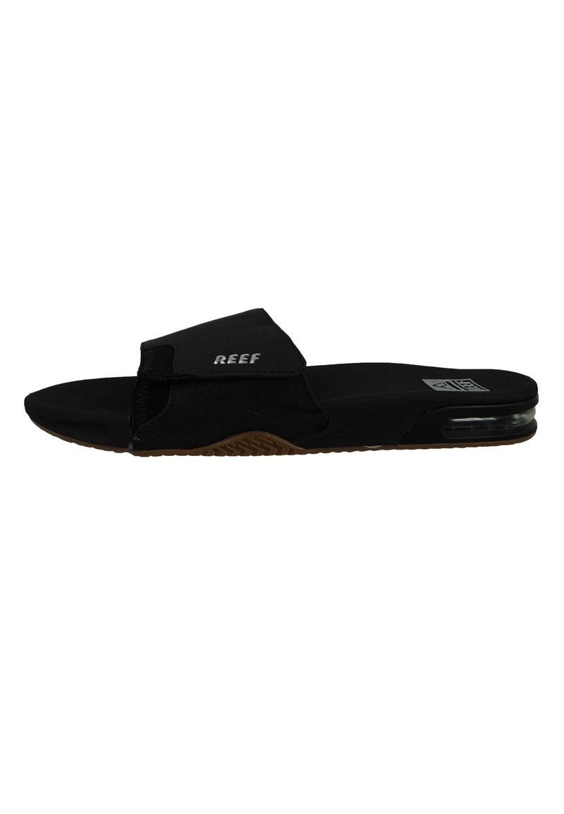 Sandales noires à glissière avec une large sangle, un design perforé et une semelle en caoutchouc avec un amortisseur d'air transparent et un traitement brun.