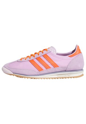 Lav selvhøj sneaker med orange striber og snørebånd, hvid mellemsål og ydersål i gummi, set fra siden.