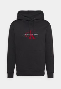 Felpa nera in cotone misto, con un logo rosso centrale "CK" e il testo "CALVIN KLEIN JEANS", tasca a marsupio e polsini a coste.