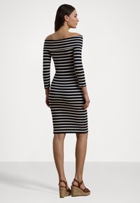 Avslappet kjole med avdekket skuldre, tettsittende korte ermer, marineblå og kremfargede horisontale striper, knelength og kombinert med brune kilehæler.