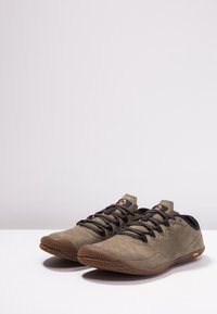Paire de chaussures décontractées légères marron à lacets avec semelles en caoutchouc texturé sur une surface blanche et un fond uni.