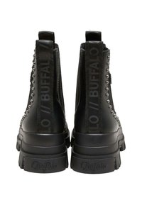 botines negros con tachuelas metálicas a lo largo de la cremallera y marca de texto en los laterales. Suela gruesa con un patrón de banda de rodadura pronunciado.