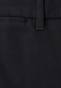 Primo piano di tessuto nero che mostra una trama testurizzata con una finitura liscia. È visibile una tasca cucita, che crea un aspetto pulito e uniforme.