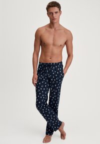 Marineblauwe pyjamabroek met een trekkoord in de taille, voorzien van een herhaald patroon van witte bomen en blauwe accenten. Gemaakt van een zacht materiaal.