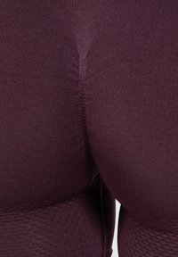 Leggings burdeos texturizados con tela suave, con un ajuste entallado y detalles de costura vertical, que muestran el diseño trasero.