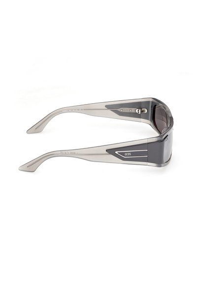Lunettes de soleil translucides gris avec verres foncés, branches épaisses, et logo "GCDS" sur le côté, présentées en vue latérale sur fond blanc.