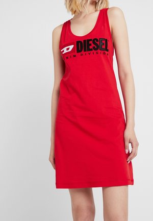 Mujer con vestido rojo sin mangas con el logo "DIESEL Denim Division" en la parte delantera sobre un fondo claro y liso.