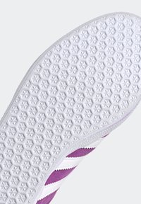 Semelle de sneaker violette et blanche avec un motif étoile texturé, en matériau caoutchouteux, de forme arrondie, et des rayures contrastées sur le côté.