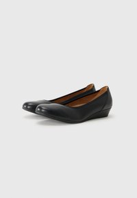 Ballerine in pelle nera con punta rotonda e un piccolo tacco a cuneo. Interno morbido e finitura esterna liscia.