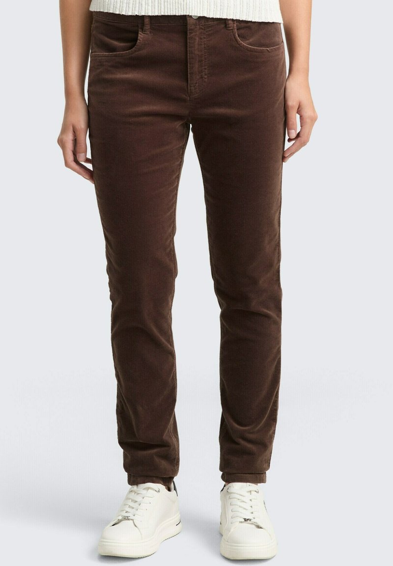 Bruine corduroy broek met een slim fit, met voorzakken en een gladde textuur, gecombineerd met witte sneakers.