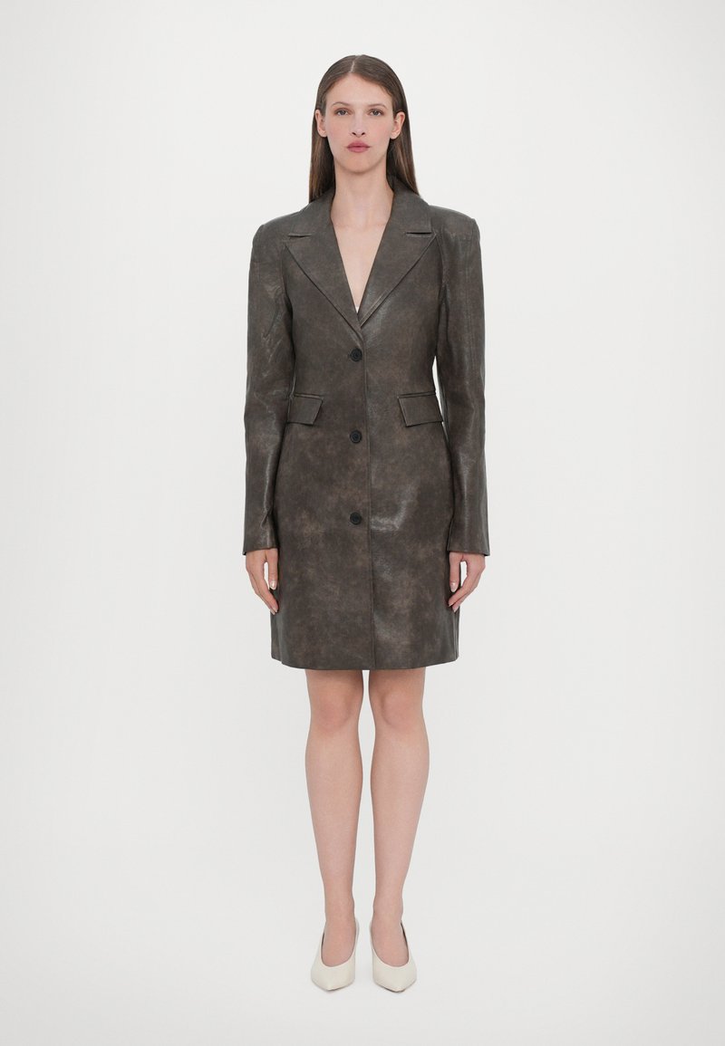 Brown leather blazer dress with a tailored fit, sharp collar, three buttons, and side pockets, ending above the knee. Smooth texture.