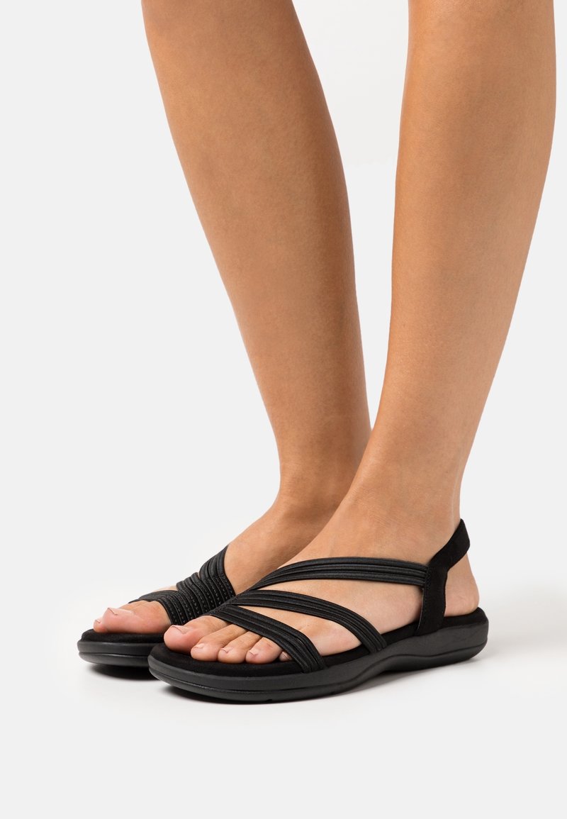 Sandales noires avec de multiples lanières entrecroisées, une semelle rembourrée et une texture lisse. Lanière au niveau du talon pour un soutien supplémentaire.