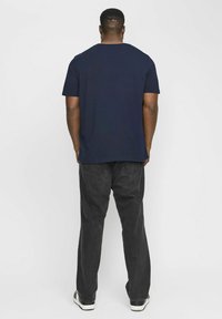 Camiseta azul marino con cuello redondo que se lleva con jeans negros. La tela parece suave y el diseño es sencillo con mangas cortas.