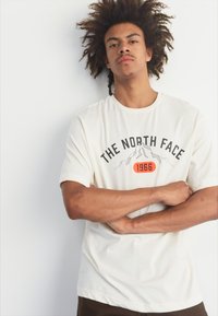 The North Face M VARSITY GRAPHIC RELAXED SS TEE - Triko s potiskem - white dune