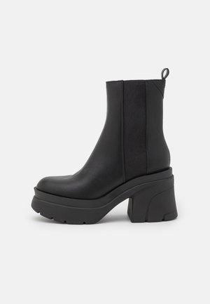 Sort læderankelstøvle med chunky platformsål, tyk blokhæle, elastisk sidespanel og trække-rem bagpå.