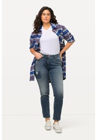 Modrá kostkovaná košile na knoflíky přes bílý V-krk tričko, zkombinovaná se sepranými modrými džíny a bílými teniskami. Uvolněný střih, neformální styl.