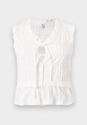 Blouse blanche sans manches en tissu froncé, avec encolure goutte d'eau et détail noué à l'avant, avec un ourlet légèrement évasé.