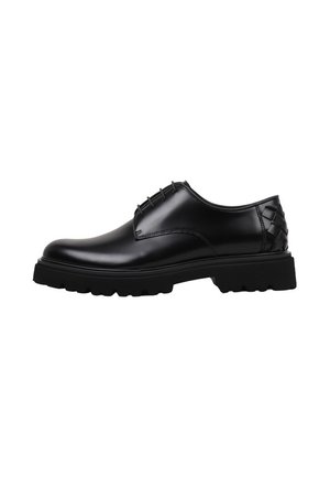 Zapato de vestir negro de cuero con cordones, suela gruesa y resistente, con detalle tejido en el talón, visto desde el lado exterior.