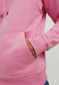 Rosa sweatshirt med dragsko, kenguruficka och ribbade ärmslut. Tyget ser mjukt och strukturerat ut, med en avslappnad passform.