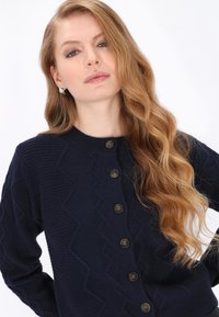 Granatowy kardigan o teksturze z wzorem w zygzak, okrągłym dekoltem i pięcioma zapięciami na guziki, wykonany z przyjemnej w dotyku dzianiny.