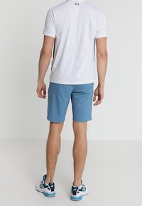 Miestenske športové oblečenie s bielym a námorníckym pruhovaným tričkom s krátkym rukávom, modrými šortkami a modro-bielymi teniskami.