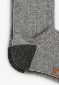 Calcetines de lana gris con textura de canalé, talón y puntera en gris oscuro reforzados, y con "SC" bordado en naranja.