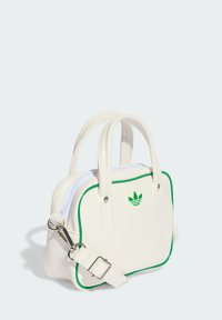 Bílá syntetická kabelka se zeleným lemem, vybavená dvěma horními madly, odnímatelným ramenním popruhem a vyšitým logem na přední straně.