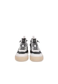 Les baskets présentent un mélange de cuir noir et blanc, des lacets gris, une semelle beige épaisse et des détails de couture remarquables.
