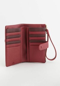 Billetera de cuero rojo con múltiples ranuras para tarjetas, acentos más oscuros contrastantes, un compartimento con cremallera y una correa para la muñeca para facilitar su transporte.