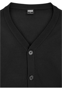 Svart cardigan med V-ringning, ribbad krage och två svarta knappar. Tillverkad av ett mjukt tyg med en enkel, minimalistisk design.