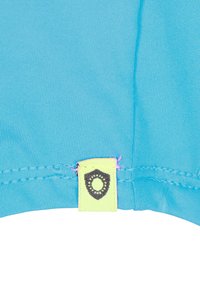 Tela turquesa con textura acanalada, que presenta una etiqueta amarilla con un ícono de escudo marrón oscuro y costura rosa en el borde.