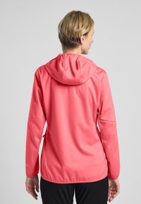 Giacca con cappuccio in corallo, realizzata in tessuto elastico, con una texture liscia e dettagli cuciti. Presenta maniche lunghe e una vestibilità regolabile.