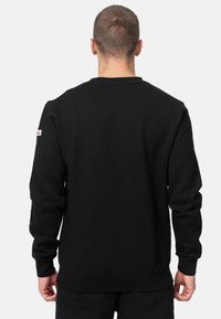 Felpa nera a manica lunga girocollo in misto cotone, con polsini a coste e un patch con logo sul braccio sinistro.