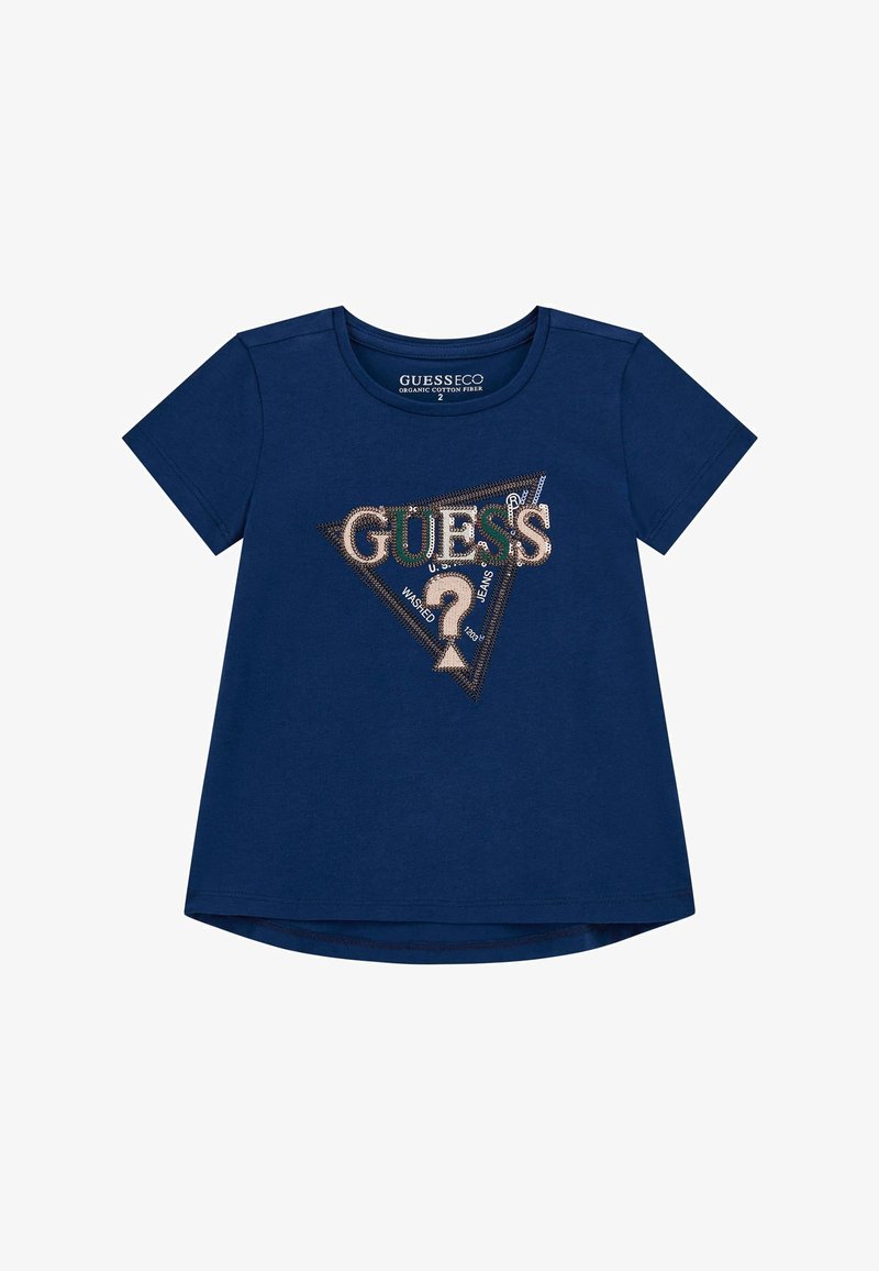 Námorně modré tričko z organické bavlny s krátkým rukávem, které má trojúhelníkový design s nápisem "GUESS" a dekorativním textem v kontrastních barvách.