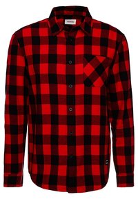 Camicia di flanella a quadretti rossi e neri, maniche lunghe, chiusura con bottoni, tasca sul petto, realizzata in tessuto morbido con superficie testurizzata.