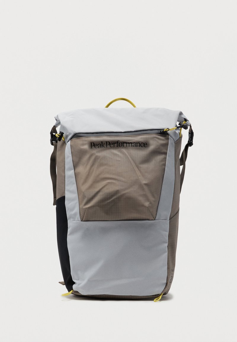 Ορθογώνιο σακίδιο πλάτης σε γκρι και μπεζ με μαύρη πλαϊνή επιφάνεια, επάνω φερμουάρ, κίτρινα τερματικά τραβήγματος και λογότυπο «Peak Performance» στην μπροστινή τσέπη.