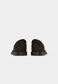 Fekete velúr slip-on cipők texturált felülettel, lekerekített orral és lapos gumitalppal. Diszkrét logó található a sarokrészen.