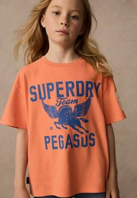 Kortärmad t-shirt i klar orange bomull med ett blått grafiskt tryck av en bevingad häst och texten "SUPERDRY Team PEGASUS".
