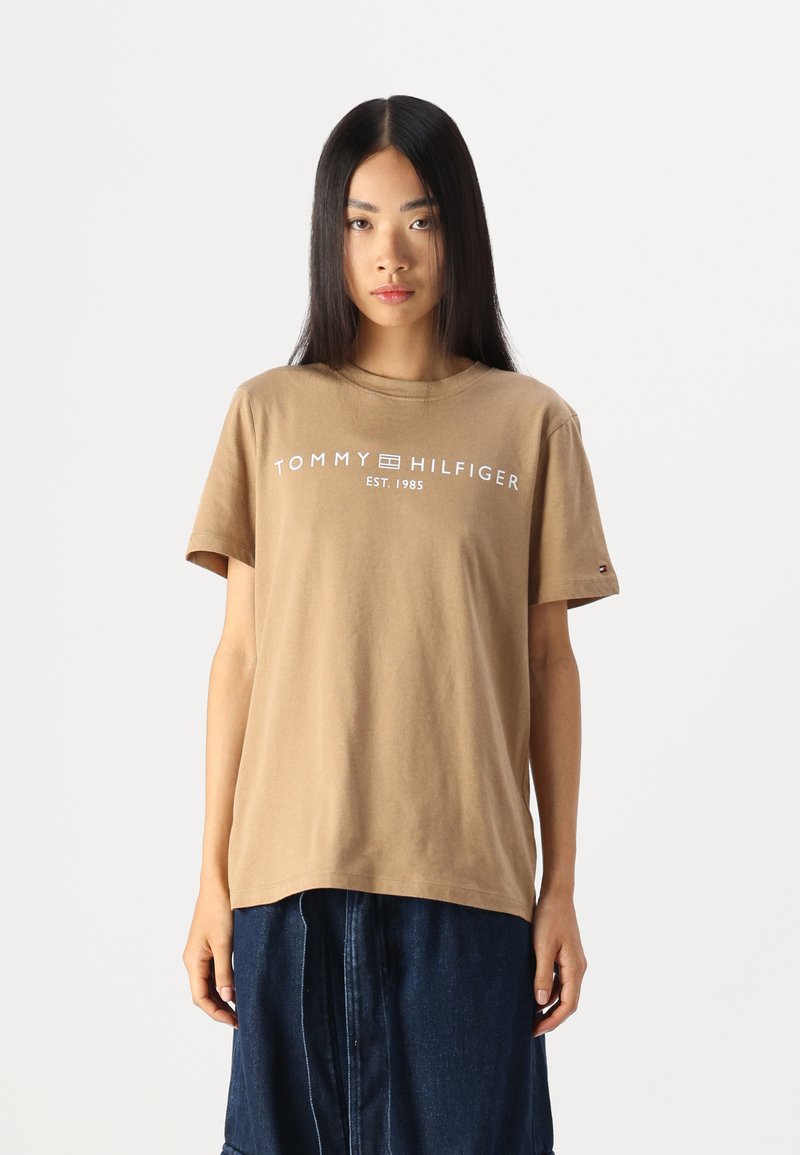 Ruda medvilnės marškinėliai trumpomis rankovėmis su apykakle, būdingi baltiems užrašams "TOMMY HILFIGER EST. 1985" ant krūtinės.
