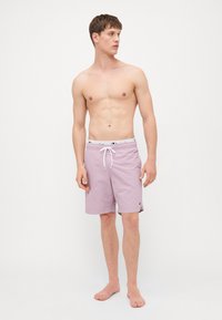 Trunch-uri de înot de culoare mov deschis, cu un elastic la talie, detaliu cu șnur și un accent mic cu logo pe lateral; material ușor și respirabil.