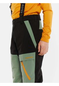 Pantaloni da sci neri e verdi con bretelle regolabili, caratterizzati da una tasca con zip arancione e dettagli con logo. Realizzati in materiale sintetico, progettati per l'attività.