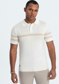 Kortärmad vit polo tröja i stickad tyg, med ljus beige horisontella ränder och ribbad nederkant, samt krage med knappar.