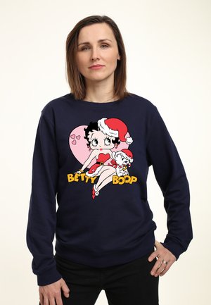 Marineblå sweatshirt med et farverigt grafisk motiv af Betty Boop iført en juleskæg, med røde accenter og hjerter på en lyserød baggrund.