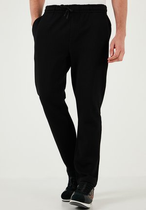 Sorte sweatpants med elastisk talje, sidelommer og afslappet pasform, lavet af et blødt, glat stof.