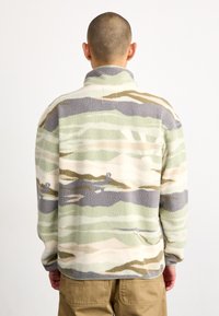 Pullover in pile con motivo camouflage verde, beige e grigio. Presenta un colletto alto e un tessuto testurizzato, con una vestibilità comoda.