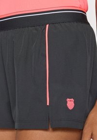 Juodos sportinės šortai su glotnia tekstūra, su rožiniu akcentu ir K-Swiss logotipu. Elastinga juostos juosta užtikrina tvirtą prigludimą.