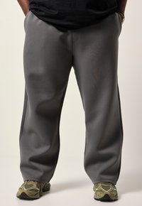 Grå sweatpants lavet af blødt stof, med lige pasform og sidesømme. Kombineret med teksturerede grønne sneakers.