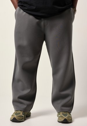 Grå sweatpants lavet af blødt stof, med lige pasform og sidesømme. Kombineret med teksturerede grønne sneakers.