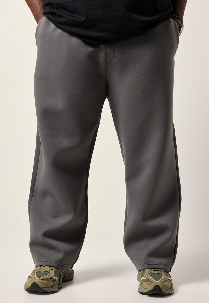 Grå sweatpants lavet af blødt stof, med lige pasform og sidesømme. Kombineret med teksturerede grønne sneakers.