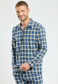 Ensemble de pyjama à manches longues en tartan bleu, noir et écru. Chemise à boutons avec col, deux poches et pantalon assorti avec une taille élastique.